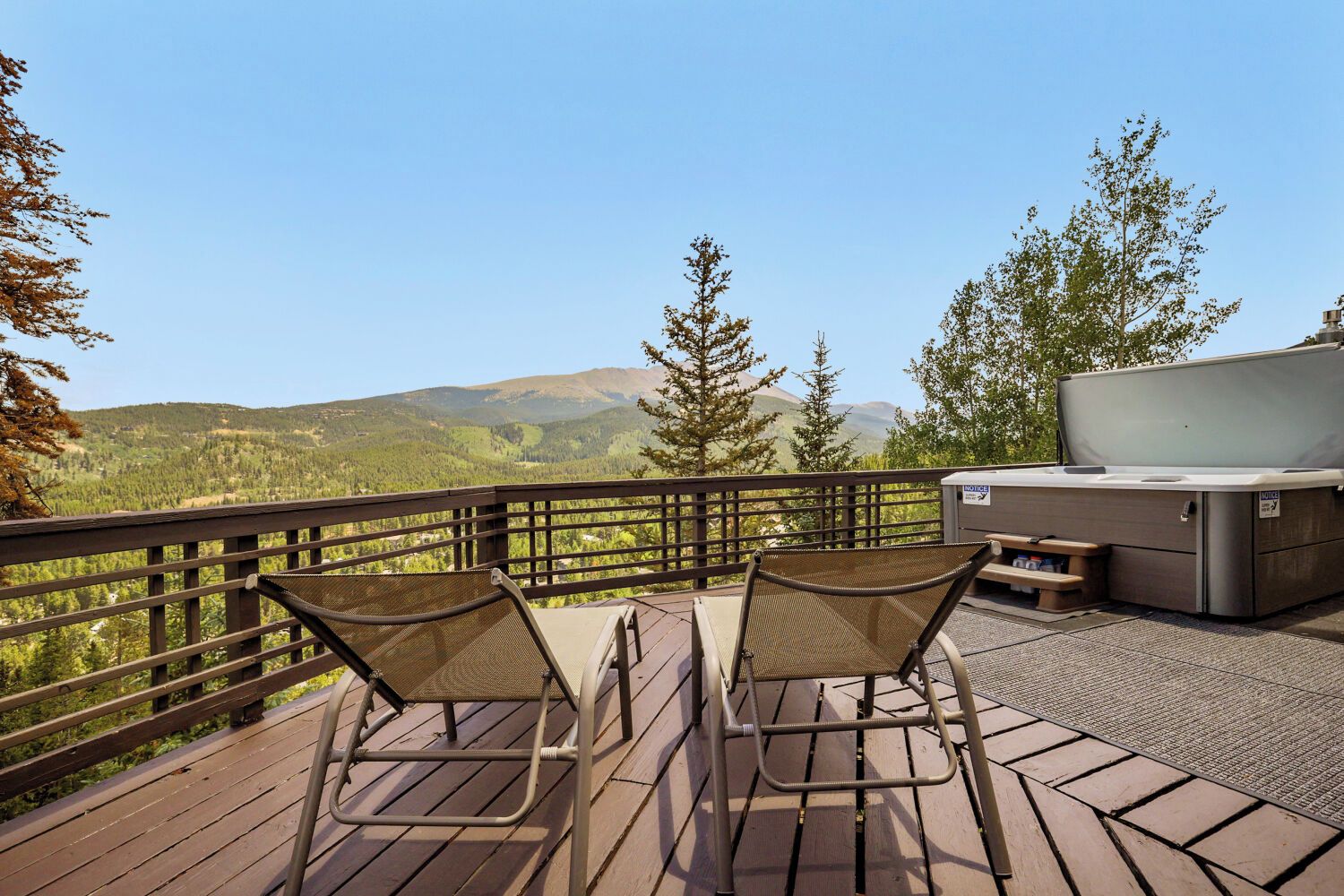 A deck with two chairs and a portable heater, overlooking a mountainous landscape.