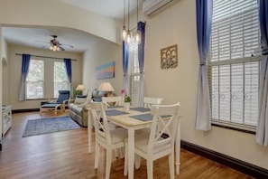 A dining area with a table and chairs, a ceiling fan, and a window with curtains.