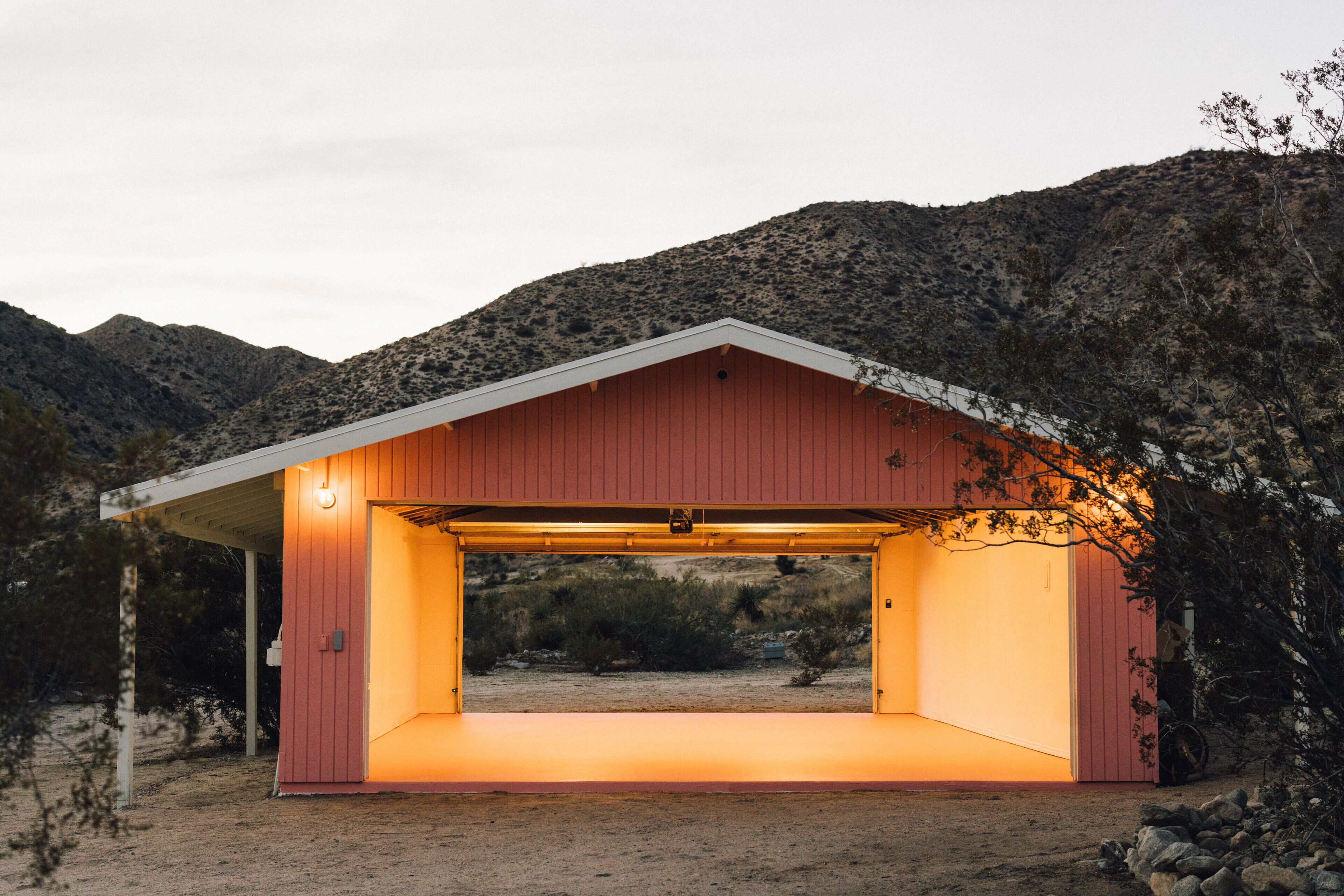 A red building with a covered entrance, surrounded by a rocky landscape and sparse vegetation.
