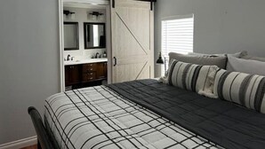 Ein Schlafzimmer mit Bett, Kommode, Spiegel und Schiebetürenschrank.