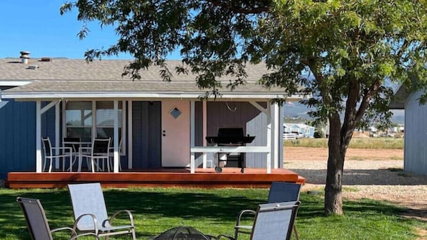 Eine Terrasse mit zwei Stühlen und einem Feuerkorb, eine überdachte Holzterrasse mit Grill sowie ein Blick auf ein Haus im Hintergrund.