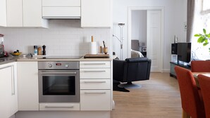 Uma cozinha moderna com armários brancos, forno embutido e máquina de café.