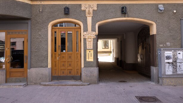 Uma entrada de prédio com porta de madeira, caixa de correio e placa na parede.
