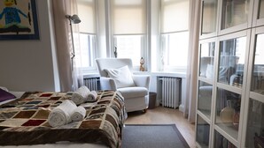 Quarto com cama, uma cadeira, radiador e guarda-roupa.