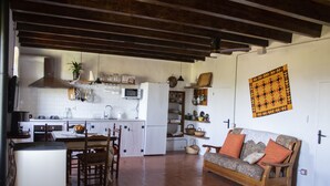 A spacious kitchen with a dining area, wooden beams on the ceiling, and a patterned wall hanging. - Charming farmhouse, surrounded by vineyards with a private pool in the  nature (Castellet i La Gornal)