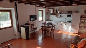 A cozy kitchen with a dining area, wooden flooring, and a TV mounted on the wall. - Charming farmhouse, surrounded by vineyards with a private pool in the  nature (Castellet i La Gornal)