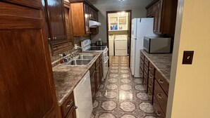 A kitchen with wooden cabinets, a microwave, a refrigerator, and a dishwasher.
