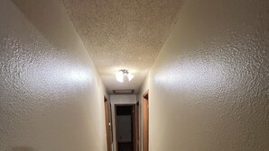 A narrow hallway with wooden flooring and white walls.