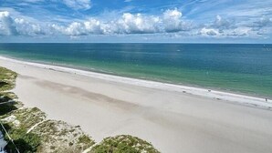 Une plage à l’eau turquoise et limpide, bordée d’un rivage sablonneux.