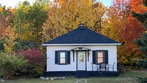 A small white house with black shutters, a chimney, and a number '500' on the door. - Cozy Home located in downtown Big Bay (Big Bay)