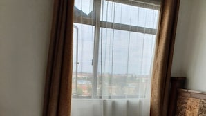 Un dormitorio con cama, cortinas, una ventana y cabecera.