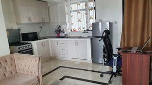 Un espacio habitable compacto con kitchenette, un sofá, una mesa de centro y una computadora portátil sobre un escritorio.