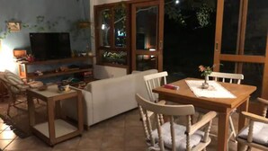 A living room with a TV, wooden furniture, and a window with a view of the outdoors.