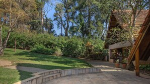 A landscaped outdoor area with a curved stone pathway leading to a wooden building with a tiled roof.