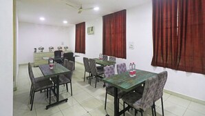 Un espace repas avec des tables et des chaises, un ventilateur de plafond et des rideaux rouges.