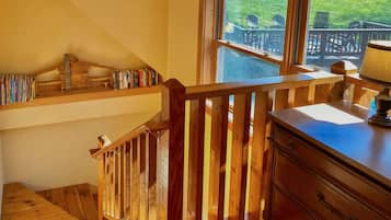 Una escalera de madera que lleva a un balcón con vistas a sillas y una mesa al aire libre.