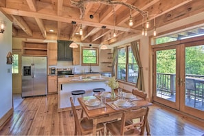 Un intérieur en bois comprenant une cuisine, un coin repas et de grandes fenêtres.