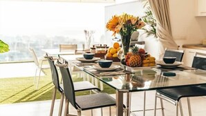 A dining area with a glass table, chairs, and a fruit bowl with oranges and pineapples. - Villa Francia (Costa Adeje)