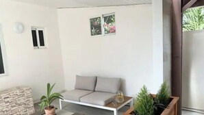 Een moderne woonkamer met een bank, salontafel en een houten plantenpot.