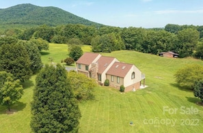 A house with a sloped roof, surrounded by a well-maintained lawn and trees. - Deerfield Diary Guest Suite (Hickory)