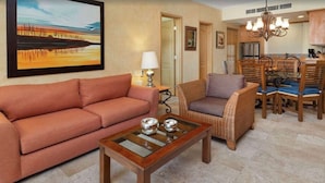 A living room with a sofa, armchair, and coffee table. There is a dining area with chairs and a chandelier. A painting is on the wall. - Beautiful Villa del Arco - Two Bedroom Suite (Cabo San Lucas)