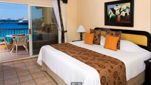 A hotel room with a bed, a painting, a chair, and a view of a body of water. - Beautiful Villa del Arco - Two Bedroom Suite (Cabo San Lucas)
