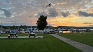 A marina with boats docked, a picnic area, and an American flag. - Stay on Main, lovely 1 bedroom renovated unit (East Jordan)