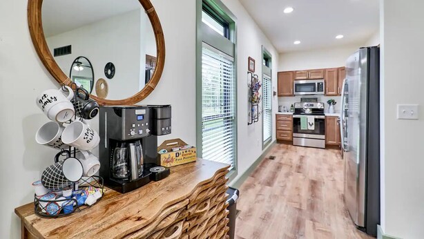 A modern kitchen with a coffee machine, wooden countertop, and a large mirror. - The Chicken Coop on Highway H (Troy)