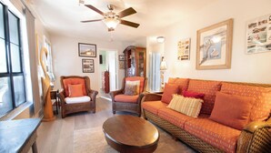 A living room with a sofa, chairs, a coffee table, and a ceiling fan.