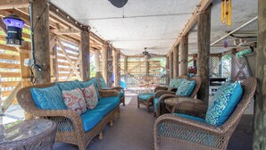 An open-air lounge with wicker furniture and a ceiling fan.