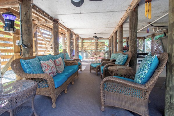 An open-air lounge with wicker furniture and a ceiling fan.