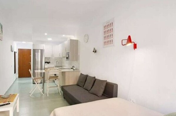 A modern, compact living space with a kitchenette, a dining area, and a bed.