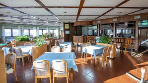 A restaurant with wooden furniture, blue tablecloths, and large windows.