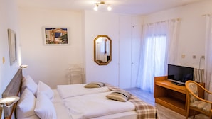 A neatly arranged hotel room with a bed, bedside table, TV, and a chair.