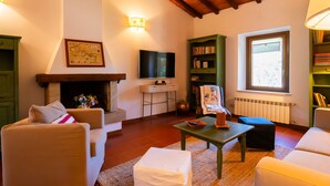 A cozy living room with a fireplace, a television, and a bookshelf. - Pimpinnacolo 1 - 2 BR M3 (Monte Argentario)