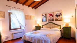 A neatly made bed with white linens, a window with a white curtain, and two bedside lamps. - Pimpinnacolo 1 - 2 BR M3 (Monte Argentario)