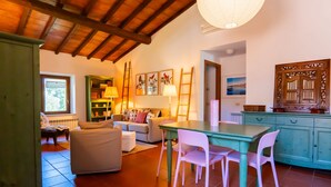 A cozy living room with a sofa, a dining table with chairs, a bookshelf, and a wooden cabinet. - Pimpinnacolo 1 - 2 BR M3 (Monte Argentario)