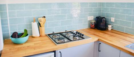 A kitchen with a gas stove, wooden countertop, and blue tiles.