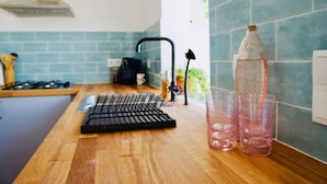 Una cocina con encimera de madera, hervidor, cafetera y una botella de agua.