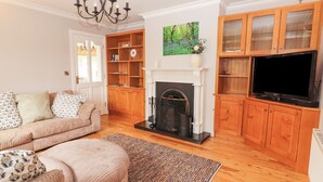Un salon avec un canapé, une cheminée, des meubles en bois et un téléviseur.