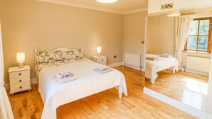 Une chambre à coucher avec un grand lit, des tables de chevet, un miroir et une fenêtre.