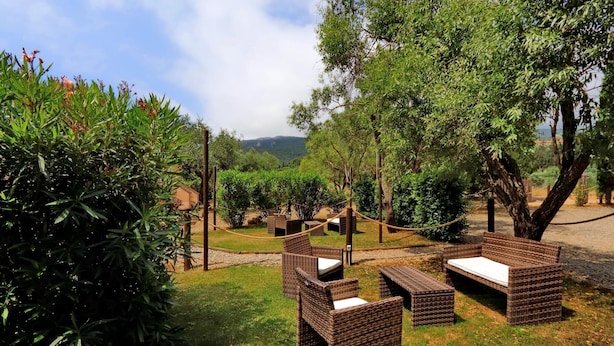 Móveis de vime ao ar livre dispostos num jardim, com vista para uma paisagem montanhosa.