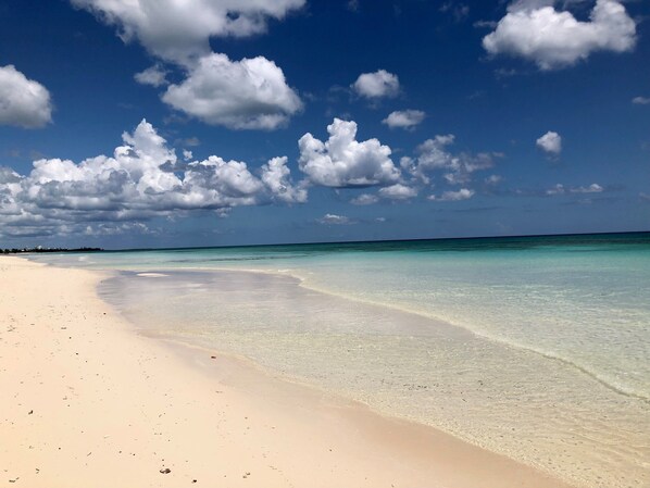 Une plage aux eaux turquoise et limpides, bordée d’une vaste étendue de sable.