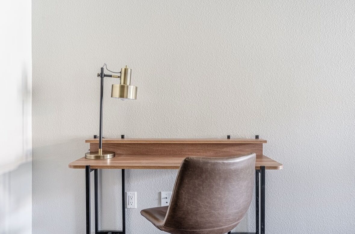 Un bureau avec une lampe et une chaise, adossé à un mur à texture.