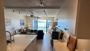A spacious kitchen with a marble countertop, a dining area with a table and chairs, and a view of the sea through large windows. - Closest to the Sandy Beach/ Direct Ocean front / Full Back up Generator (East End, St Thomas)