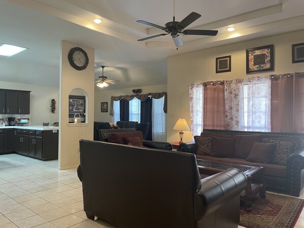 A living room with a sofa, a coffee table, and a lamp. There is a ceiling fan and a clock on the wall.