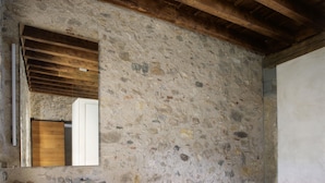 A bathroom with a stone wall, a wooden ceiling, and a built-in sink.