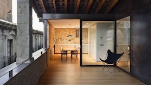 A modern interior with a wooden floor, a dining area with a table and chairs, and a kitchen with a stone backsplash.