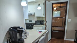 A compact kitchen with a dining table, chairs, a coffee maker, and a microwave.
