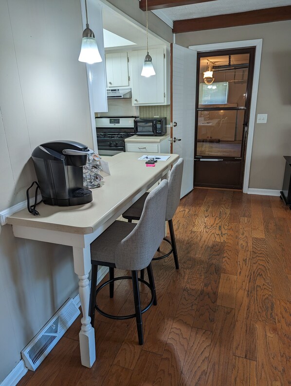 A compact kitchen with a dining table, chairs, a coffee maker, and a microwave. - Cozy and Quiet Three Bedroom Two Bathroom Ranch (Kokomo)